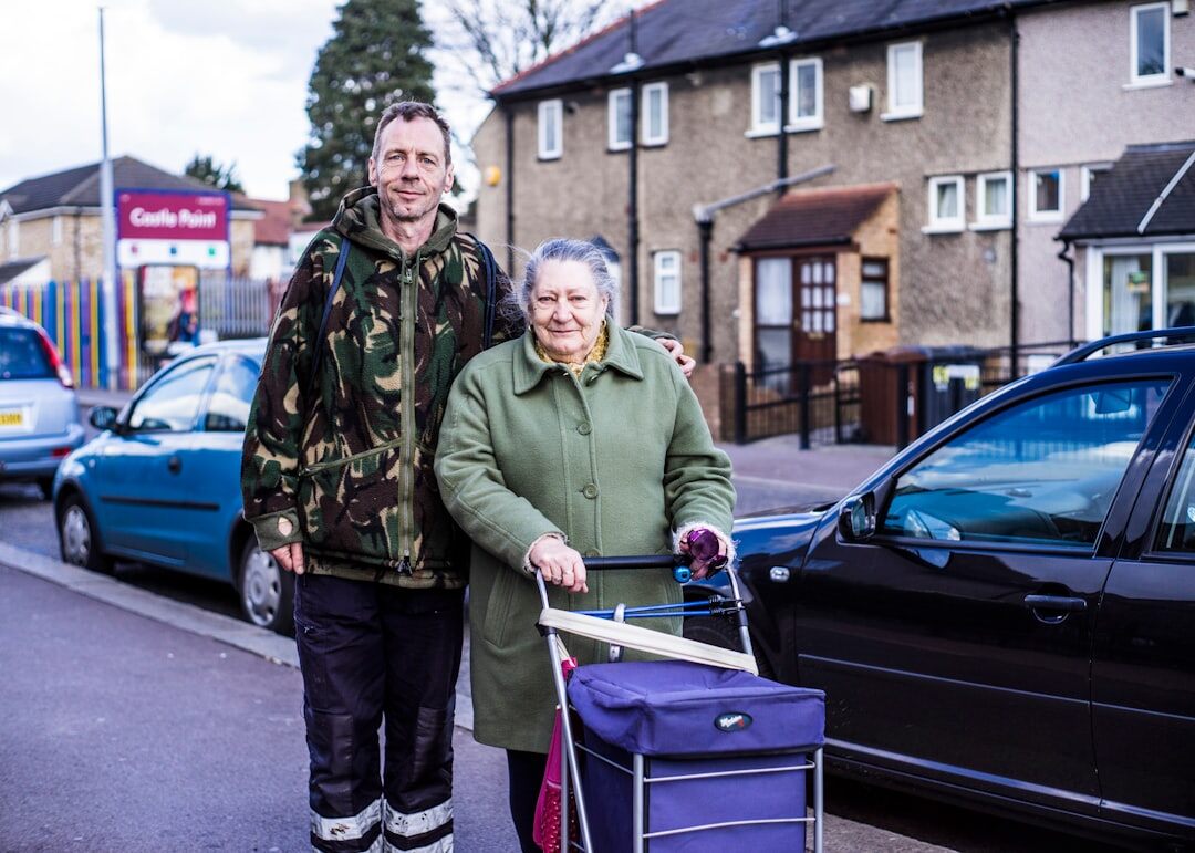 Younger volunteer helping an elderly person carry groceries and smiling