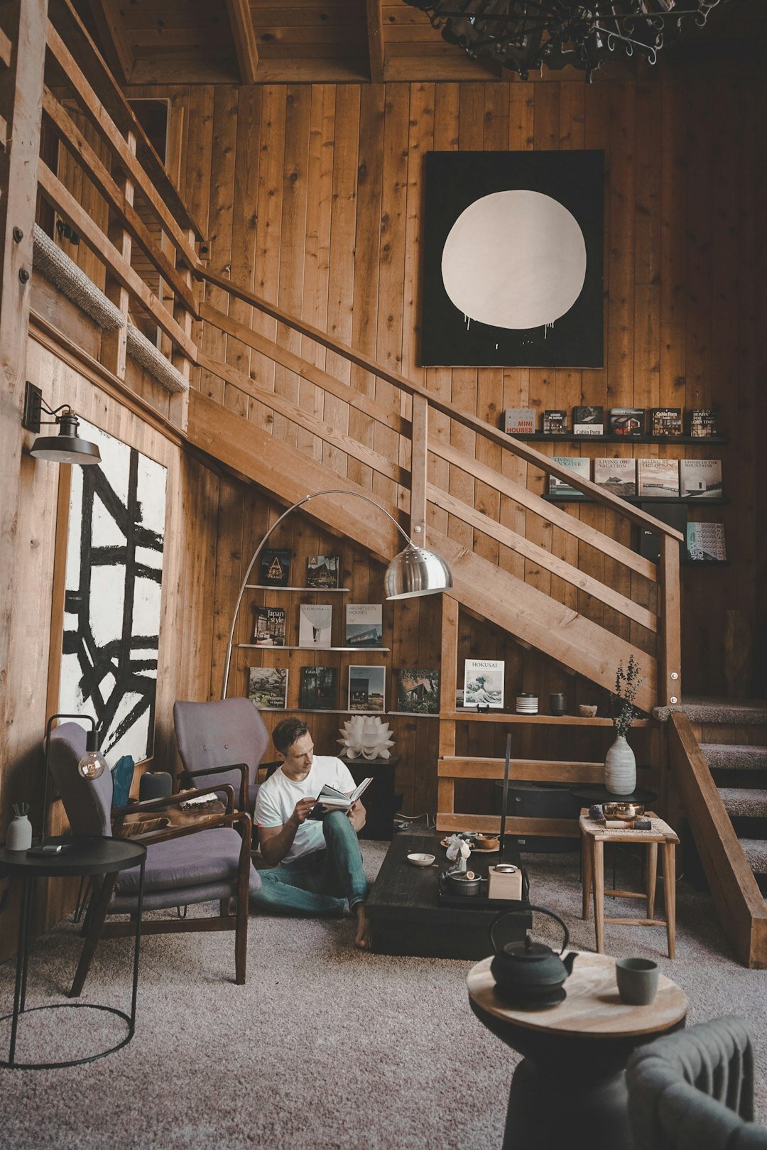 Elderly woman reading a book aloud to a small seated group in a cozy room