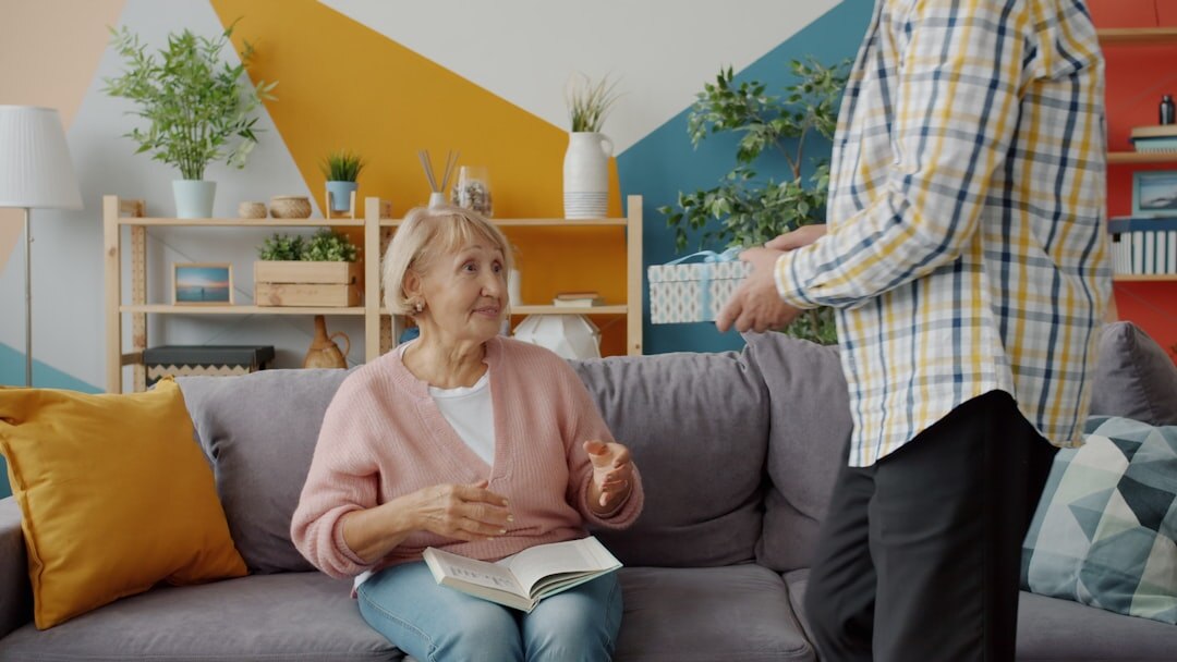 Adult daughter visiting and hugging her elderly mother in a bright living room