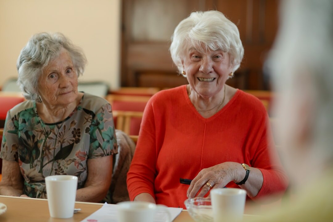 Group of smiling elderly friends sitting together at a table sharing coffee and conversation